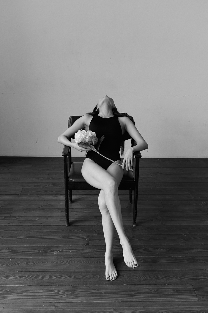 Grayscale Photo of a Woman in Her Black Leotards Sitting on the Chair